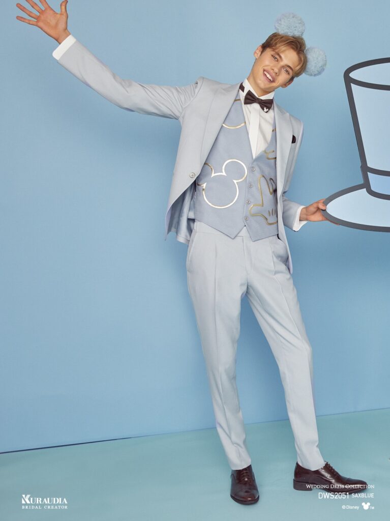 DWS2051(サックスブルー)| くすみ感のあるマットなサックスブルー素材をジャケット&パンツに使用し、ベストにはドレスと同素材の「ミッキー」のパーツをモチーフにした箔チュールモチーフをあしらい、同色系のコントラストで上品なカラーコントラストにまとめたシングル×1ツ釦、ピークドラペルのタキシードです。