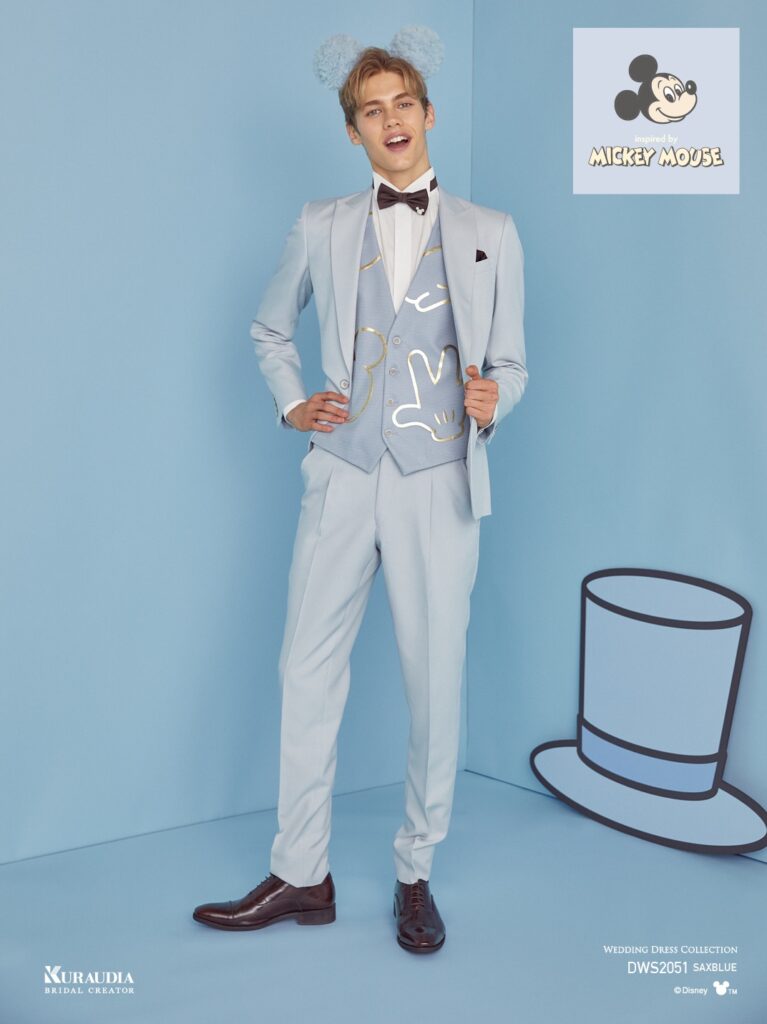 DWS2051(サックスブルー)| くすみ感のあるマットなサックスブルー素材をジャケット&パンツに使用し、ベストにはドレスと同素材の「ミッキー」のパーツをモチーフにした箔チュールモチーフをあしらい、同色系のコントラストで上品なカラーコントラストにまとめたシングル×1ツ釦、ピークドラペルのタキシードです。
