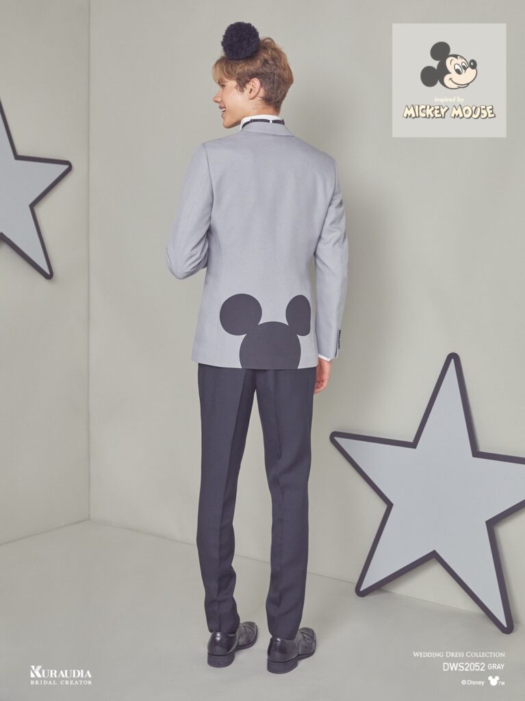 DWS2052(グレー)|ミディアムからライトトーンのマットなトップグレー素材を使用したジャケットに背面裾から半分覗いているような配置でミツマルの大きなプリントをあしらった、シングル×2ツ釦、ノッチドラペルのジャケ&スラ異素材コーデのタキシードです。ベストにはミツマルモチーフの連続柄ジャガードを使用、胸ポケットにはポケットチーフ代わりにミツマルのワッペンで随所に「ミッキー」要素を纏めました。