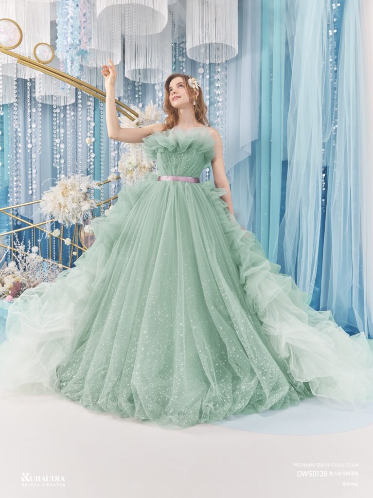 DWS0138 Blue Green 「Ariel」| 波のゆらめきを表現したタッキングのスカートがポイントの、「アリエル」からインスパイアされたボリュームドレスです。 ブルーグリーンの美しいグラデーションと、パープルのウエストリボンが「アリエル」らしいカラーリングです。バルーンデザインの裾やタッキングのスカートの内側からは海の中の光をイメージしたグリッターが光輝きます。動きのある立ち上がったドレープ身頃には海の泡を表現したパールやビーズがあしらわれています。