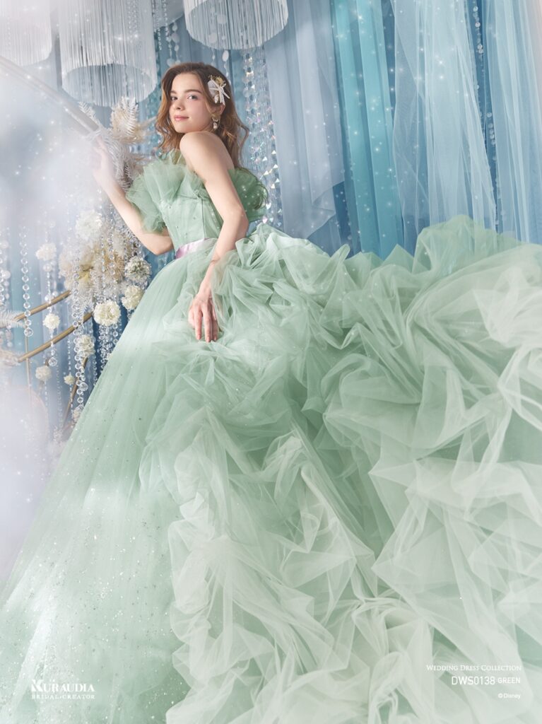 DWS0138 Blue Green 「Ariel」| 波のゆらめきを表現したタッキングのスカートがポイントの、「アリエル」からインスパイアされたボリュームドレスです。 ブルーグリーンの美しいグラデーションと、パープルのウエストリボンが「アリエル」らしいカラーリングです。バルーンデザインの裾やタッキングのスカートの内側からは海の中の光をイメージしたグリッターが光輝きます。動きのある立ち上がったドレープ身頃には海の泡を表現したパールやビーズがあしらわれています。