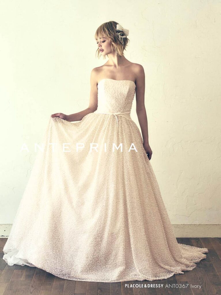 ANT0367(アイボリー/オレンジ) | ジュエルパールグリッターの輝きを全身にまとい、上品さと可憐さをあわせ持つ“現代のプリンセス”を表現。新素材“エアーファブリックオーガン”が、ふんわりと空気を含んだような軽やかなドレープを描きます。ピーチオレンジのやさしい色合いが肌にやわらかく映え、見る人にぬくもりと幸せを届けるような一着です。