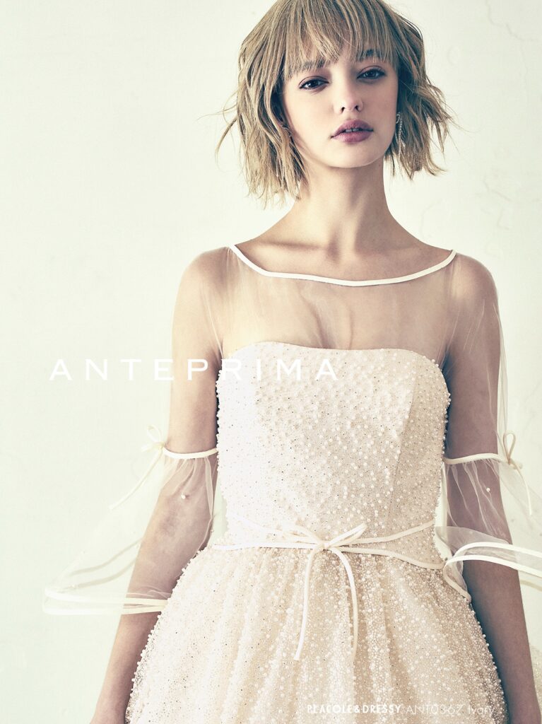 ANT0367(アイボリー/オレンジ) | ジュエルパールグリッターの輝きを全身にまとい、上品さと可憐さをあわせ持つ“現代のプリンセス”を表現。新素材“エアーファブリックオーガン”が、ふんわりと空気を含んだような軽やかなドレープを描きます。ピーチオレンジのやさしい色合いが肌にやわらかく映え、見る人にぬくもりと幸せを届けるような一着です。