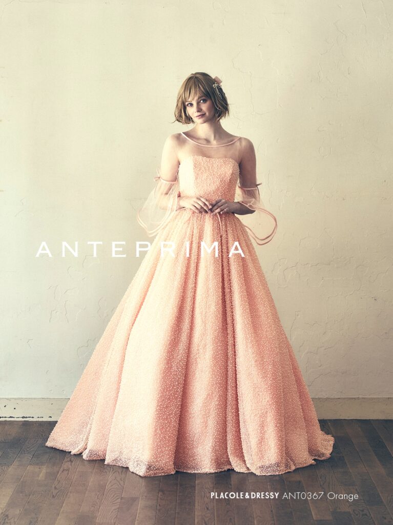 ANT0367(アイボリー/オレンジ) | ジュエルパールグリッターの輝きを全身にまとい、上品さと可憐さをあわせ持つ“現代のプリンセス”を表現。新素材“エアーファブリックオーガン”が、ふんわりと空気を含んだような軽やかなドレープを描きます。ピーチオレンジのやさしい色合いが肌にやわらかく映え、見る人にぬくもりと幸せを届けるような一着です。