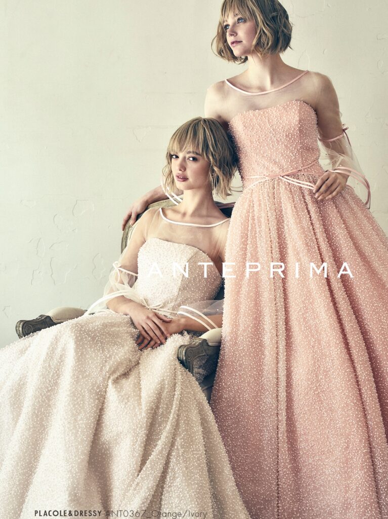 ANT0367(アイボリー/オレンジ) | ジュエルパールグリッターの輝きを全身にまとい、上品さと可憐さをあわせ持つ“現代のプリンセス”を表現。新素材“エアーファブリックオーガン”が、ふんわりと空気を含んだような軽やかなドレープを描きます。ピーチオレンジのやさしい色合いが肌にやわらかく映え、見る人にぬくもりと幸せを届けるような一着です。